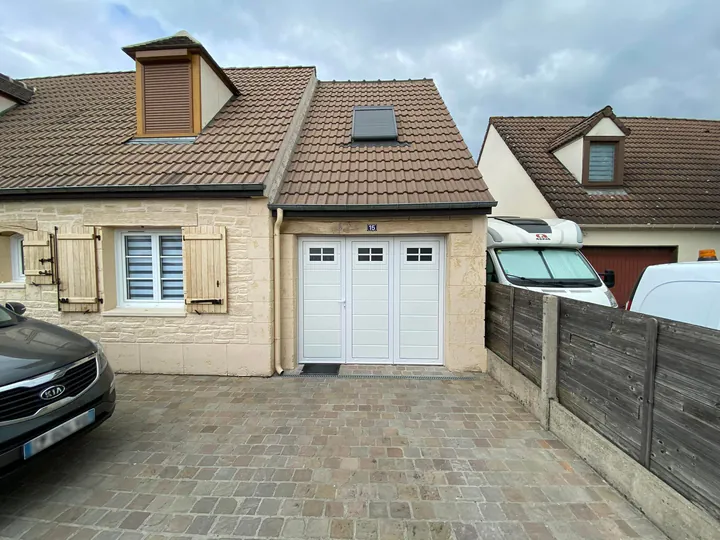 Porte de garage blanche posée sur une maison en pierre