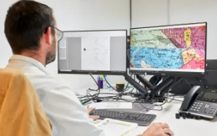 Ingénieur travaillant sur des plans devant deux écrans